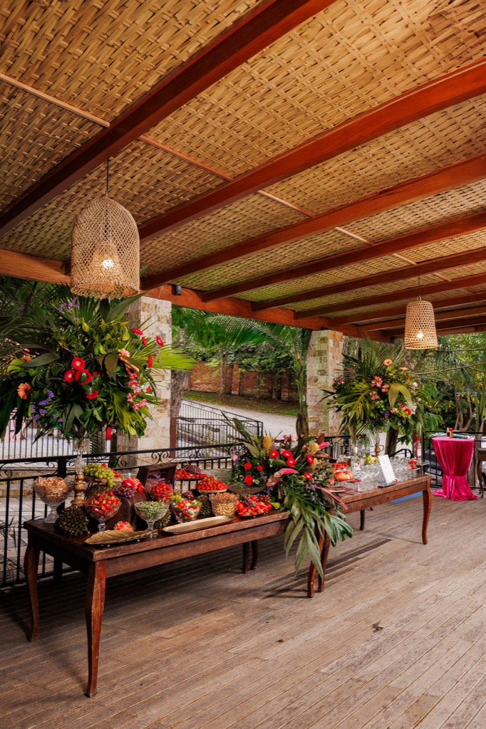 Deck coberto na Chácara do Cris — mesas bistrô com banquetas coloridas
