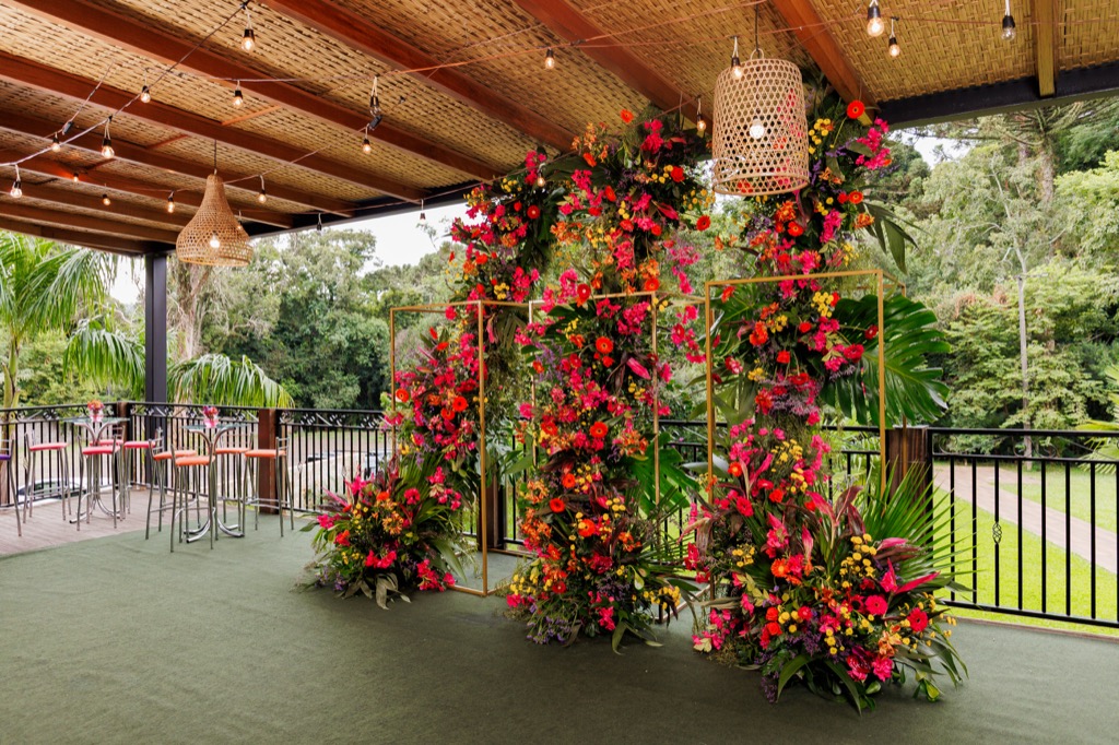 Deck coberto na Chácara do Cris — instalação floral com molduras douradas
