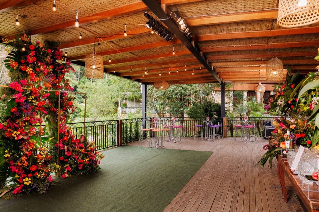 Deck coberto na Chácara do Cris — vista ampla com decoração floral