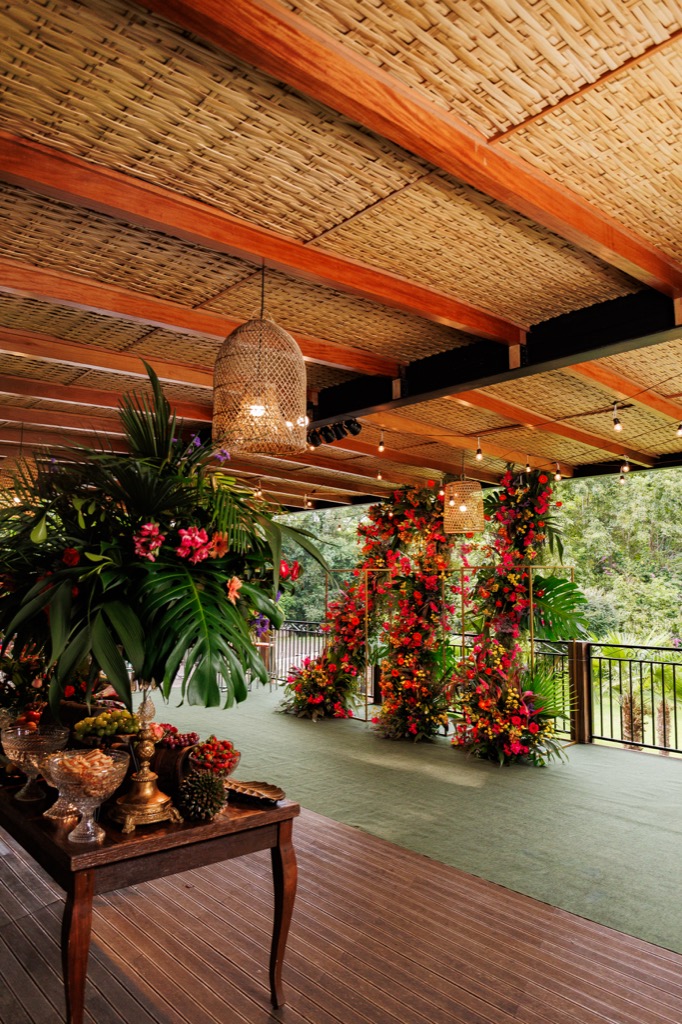 Deck coberto na Chácara do Cris — mesa de buffet com arranjo tropical