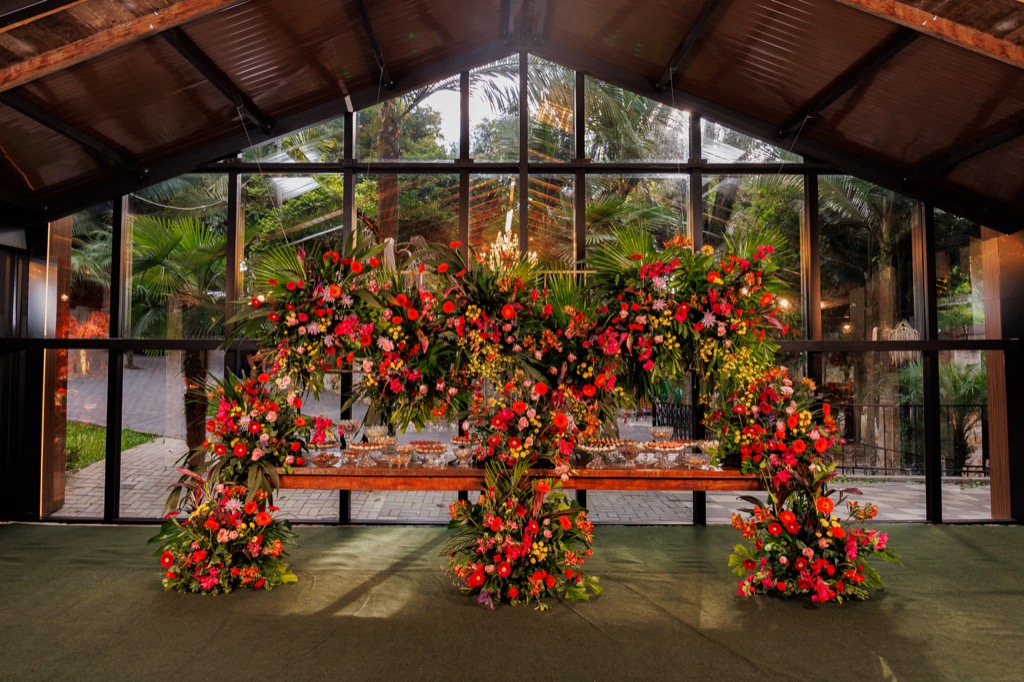 Salão de eventos na Chácara do Cris — mesa com arranjo floral e painel de LED