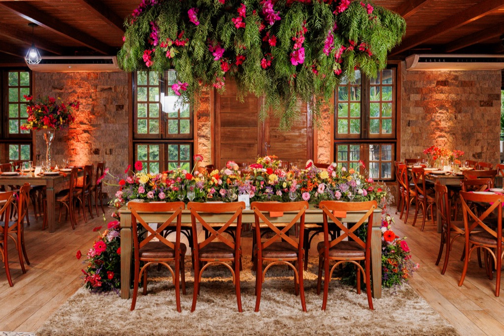 Salão de eventos na Chácara do Cris — mesa com arranjo floral e janelas de vidro